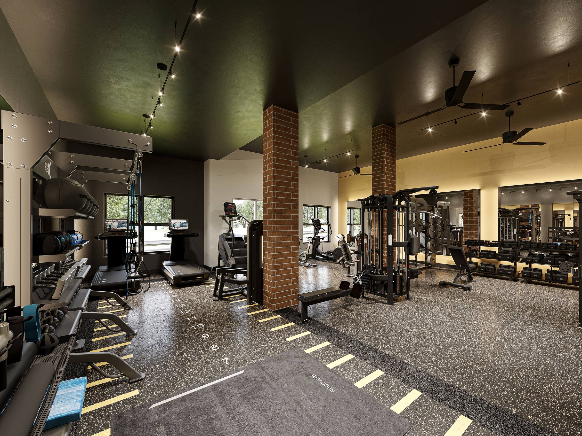 Modern gym with treadmills, weight racks, benches, and large windows letting in natural light. Brick pillars divide the workout areas.